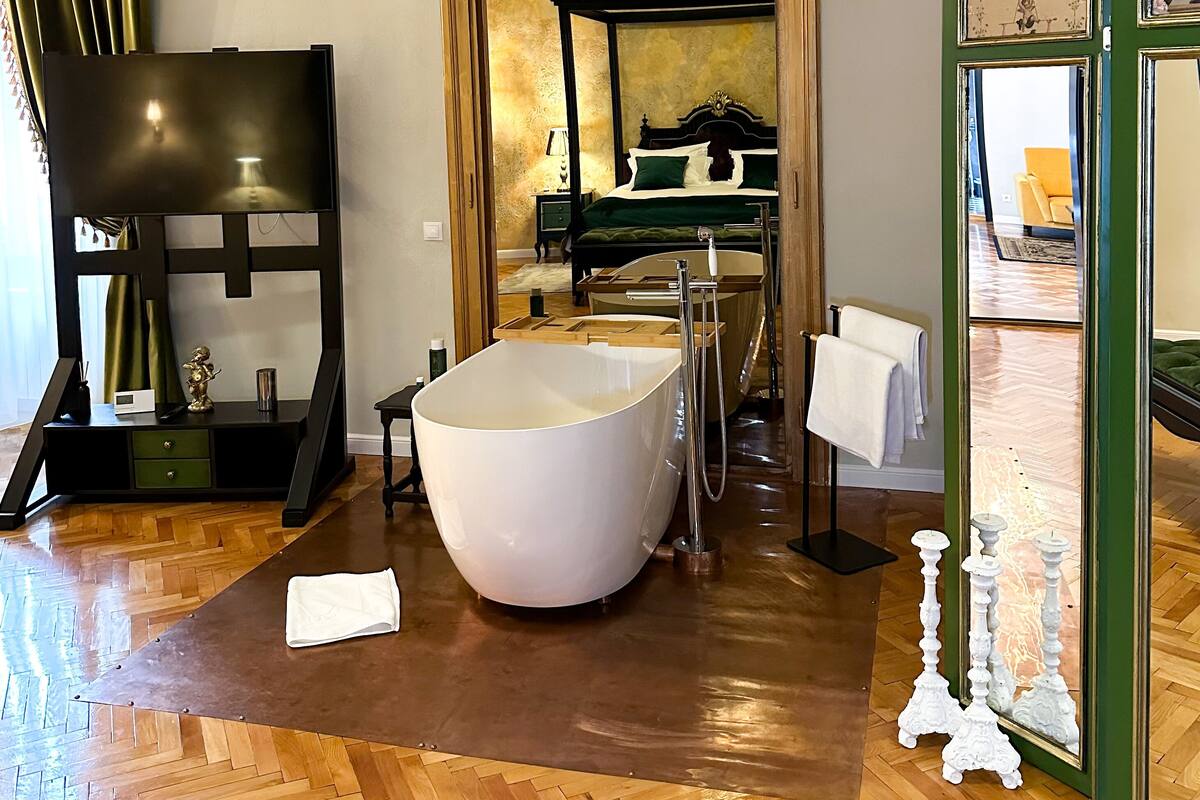 A spacious bathroom with a freestanding bathtub, a wooden vanity, and a large mirror.
