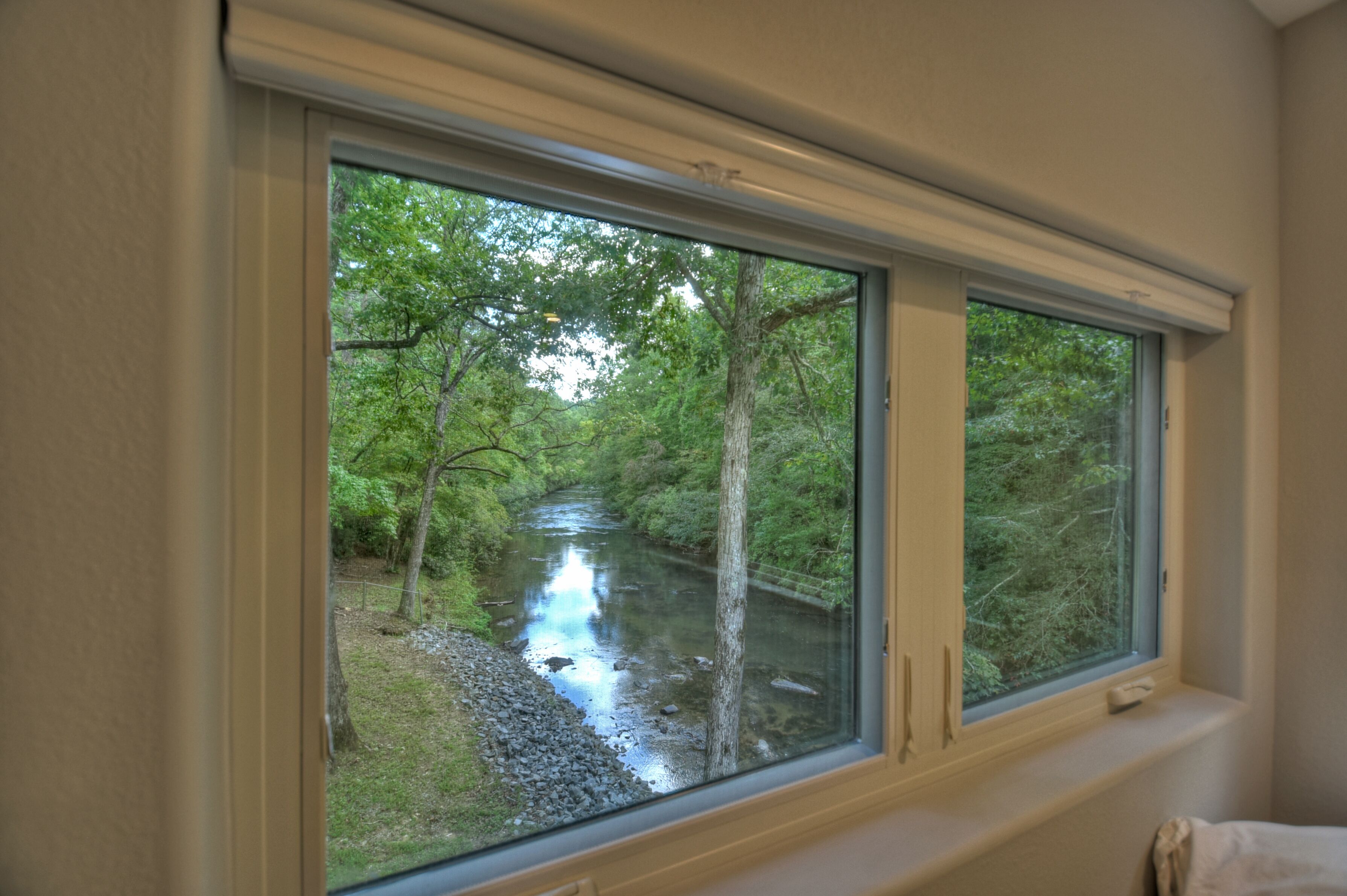 A window with a view of a river surrounded by trees.