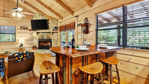 Ein rustikaler Holzraum mit Kamin, Bar und Fernseher.