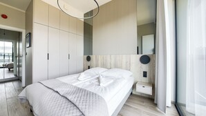 A modern bedroom with a large bed, built-in wardrobes, and a minimalist design. - Apartamenty Sun & Snow Shellter (Trzebiatow)