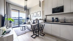 A modern kitchen with a built-in oven, a dining area with a table and chairs, and a sofa. - Apartamenty Sun & Snow Shellter (Trzebiatow)