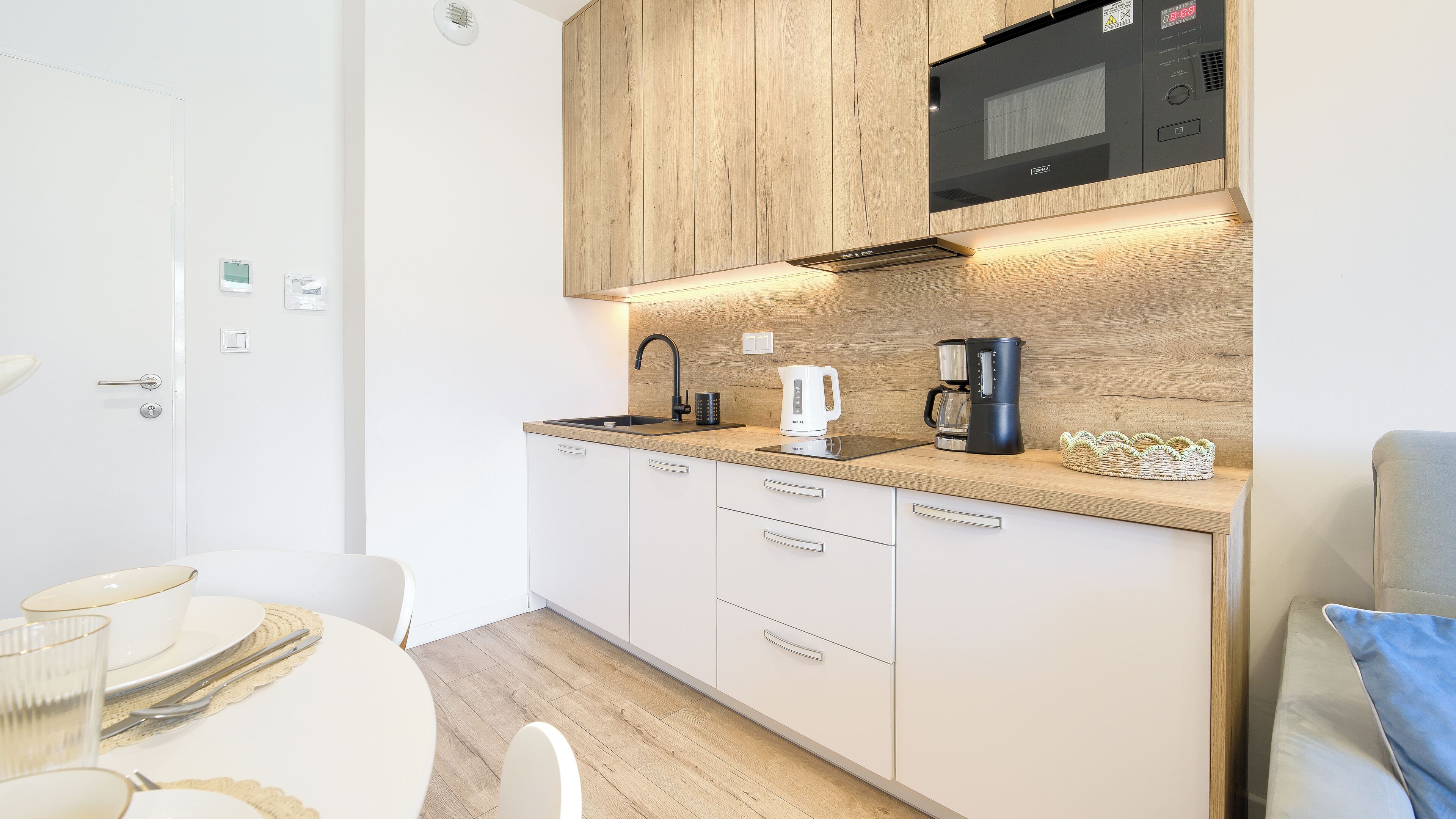 A compact kitchen with a microwave, coffee maker, and kettle on the countertop.