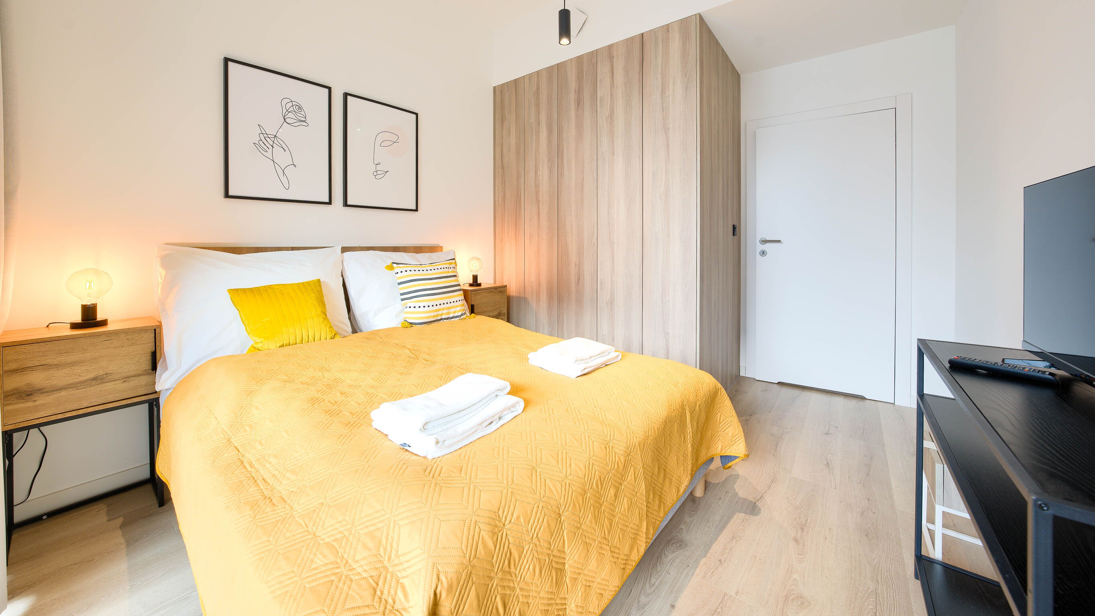 Et pænt indrettet hotelværelse med seng, natbord og et TV-møbel.