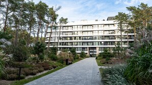 A modern multi-story building with a paved walkway leading to the entrance. - Apartamenty Sun & Snow Shellter (Trzebiatow)