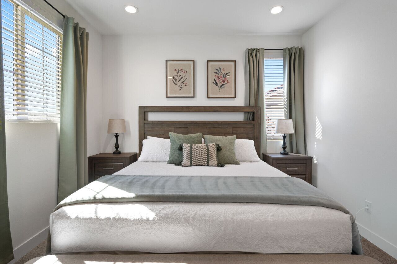 Un dormitorio ordenado con una cama grande, dos mesitas de noche y un cabecero.