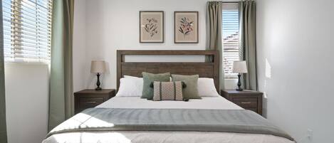 Un dormitorio ordenado con una cama grande, dos mesitas de noche y un cabecero.