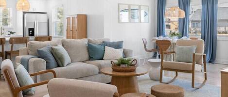 A modern living room with a sectional sofa, wooden chairs, a coffee table, and a dining area.