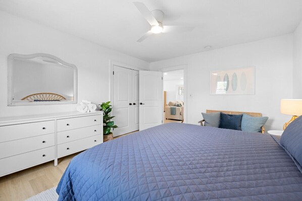 Un dormitorio con una cama grande, un aparador, un espejo y un ventilador de techo.