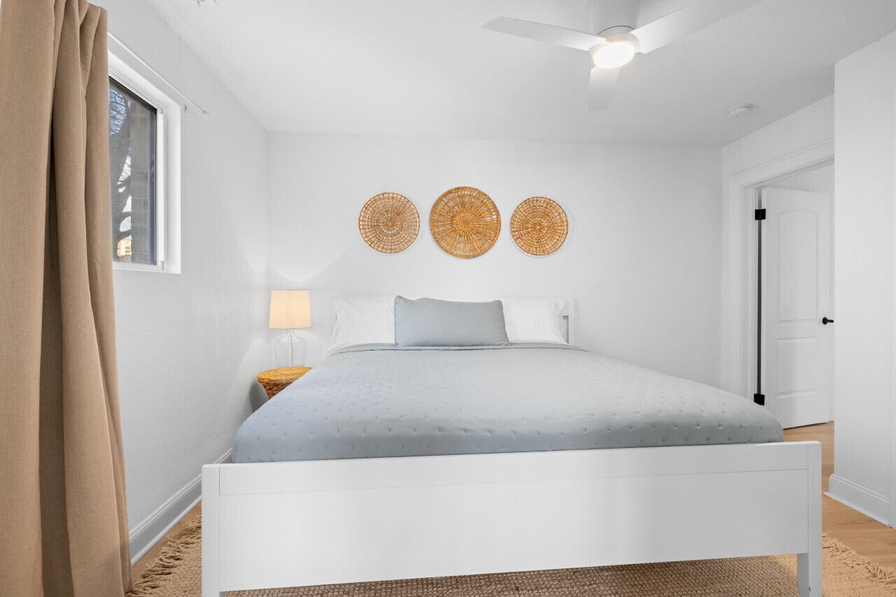 Une chambre avec un lit blanc, un ventilateur de plafond et trois décorations circulaires fixées au mur.