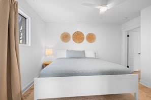 Ein Schlafzimmer mit einem weißen Bett, einem Deckenventilator und drei runden Wanddekorationen.