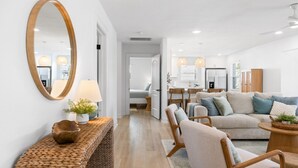 A modern living room with a sofa, chairs, a coffee table, and a large mirror.