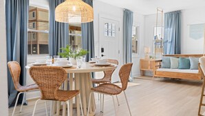 A dining area with wicker chairs, a round table, and a hanging light fixture.