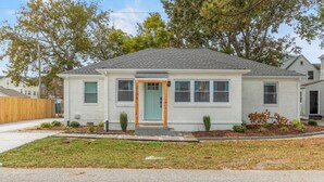 A single-story house with a front door, windows, and a small front yard with plants.