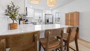 A modern kitchen with white cabinetry, a central island, and two hanging pendant lights.