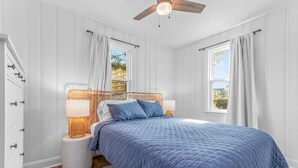 Un dormitorio con una cama grande, dos lámparas de noche, un ventilador de techo y vistas de edificios.