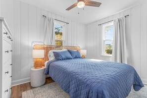 Ein Schlafzimmer mit einem großen Bett, zwei Nachttischlampen, einem Deckenventilator und Blick auf Gebäude außerhalb.