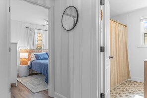 Ein Schlafzimmer mit Bett, Nachttisch, Lampe und einem Fenster mit Vorhängen.