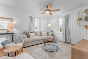 Ein Wohnzimmer mit Sofa, Couchtisch und Deckenventilator.