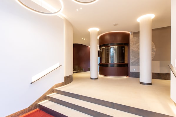 A modern interior with a central elevator, a staircase, and a polished floor. - Daplace - Corso Sempione Suites (Milan)