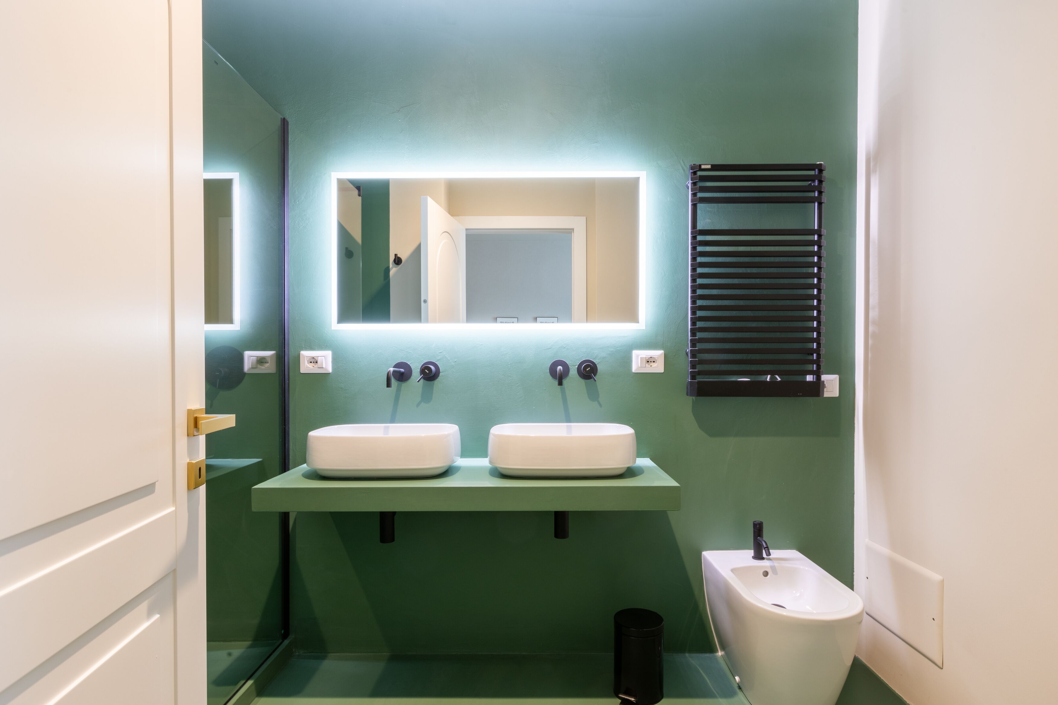 A bathroom with two sinks, a mirror, and a bidet.