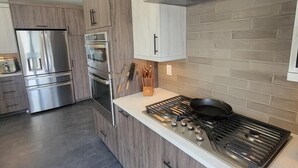 A modern kitchen with wooden cabinets, stainless steel appliances, and a gas stove. - Webster Lake Escape! (Franklin)