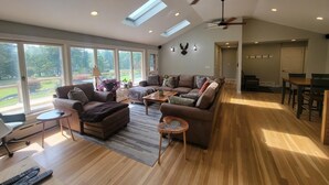 A spacious living room with a high ceiling, large windows, and a ceiling fan. - Webster Lake Escape! (Franklin)