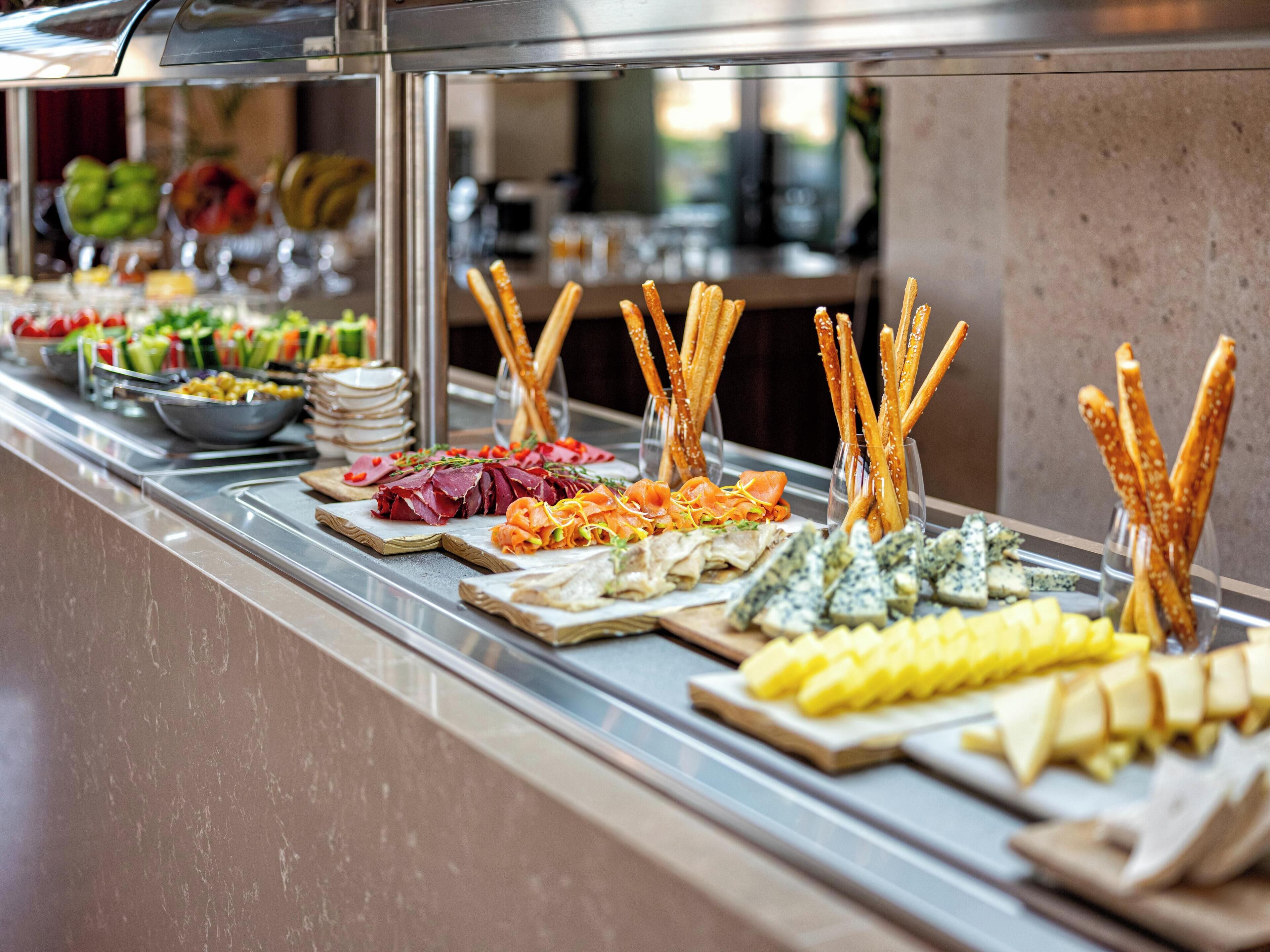 A buffet with various food items including meats, cheeses, and vegetables.
