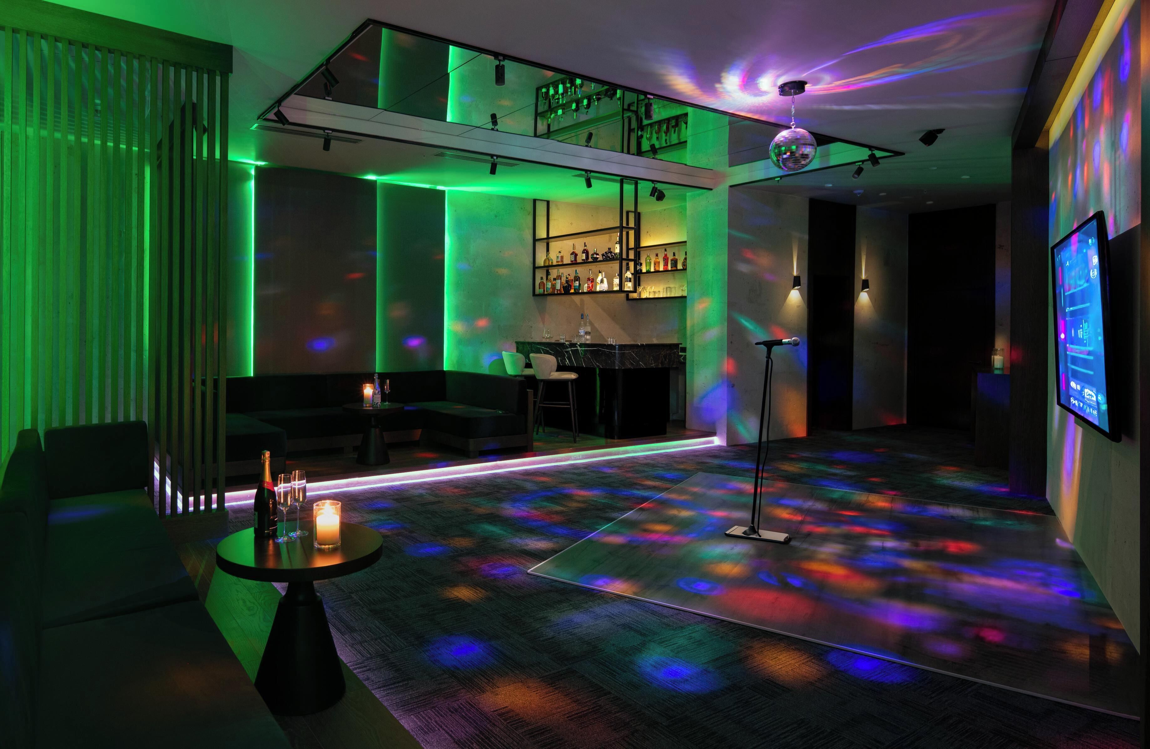 A modern bar area with a bar counter, seating, and a DJ booth.