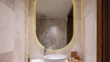 Un baño con un espejo ovalado grande, un lavabo blanco y un mueble de tocador de madera.