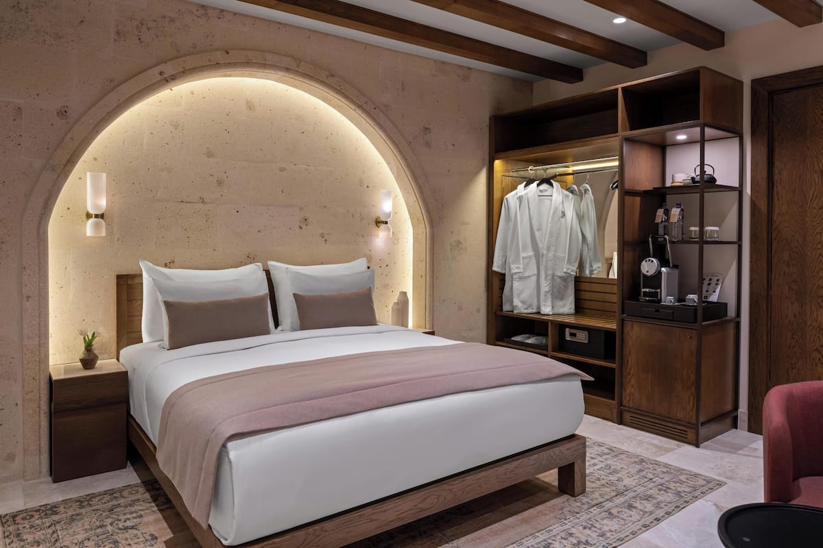 Un dormitorio con una cama grande, cabecera de madera y un armario empotrado con estantes y espacio para colgar.