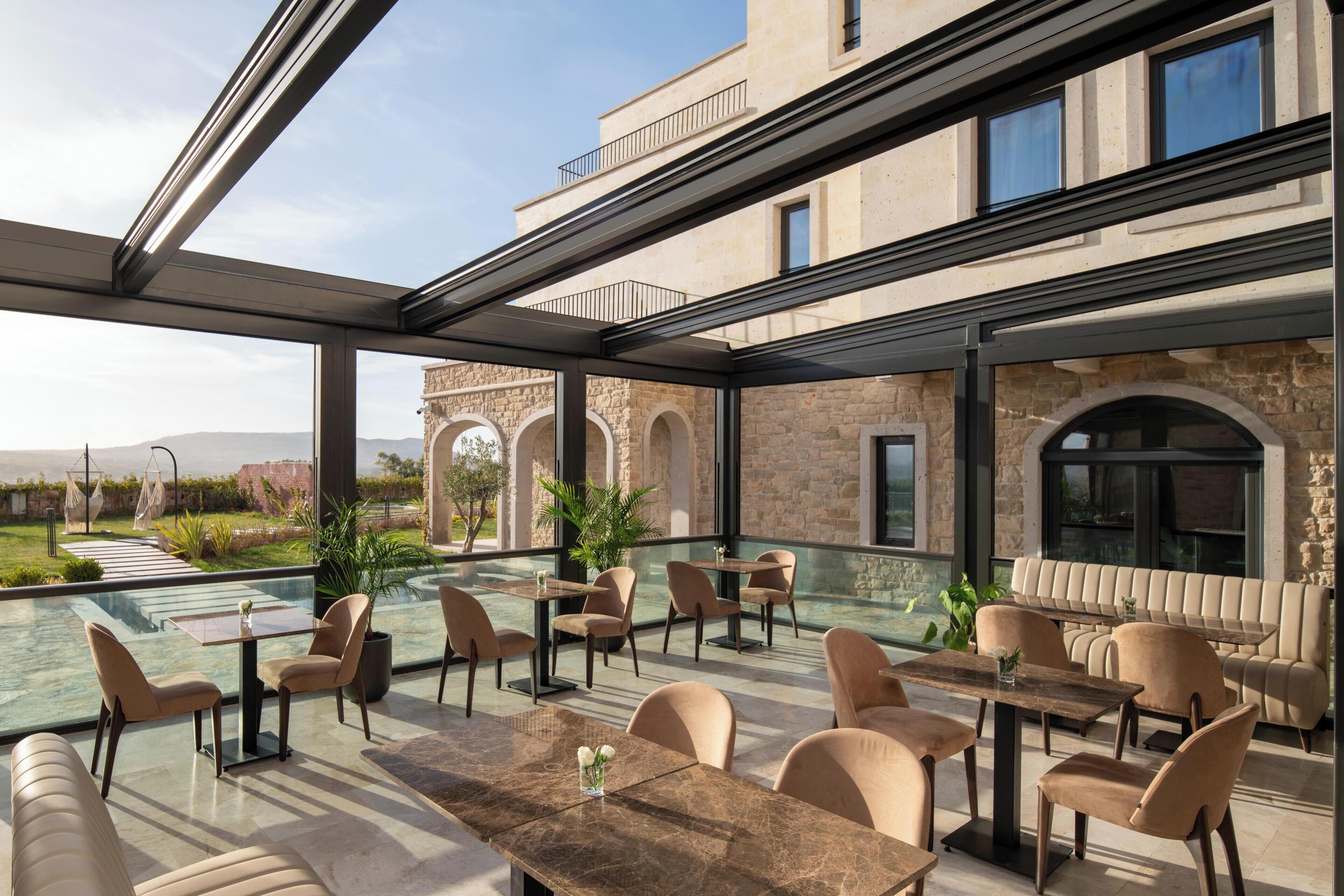An outdoor dining area with tables and chairs, a pool, and a view of a historic building.