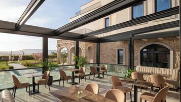 An outdoor dining area with tables and chairs, a pool, and a view of a historic building.
