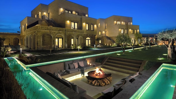 Un hotel moderno con piscina, zona de estar exterior y un hogar para la chimenea.