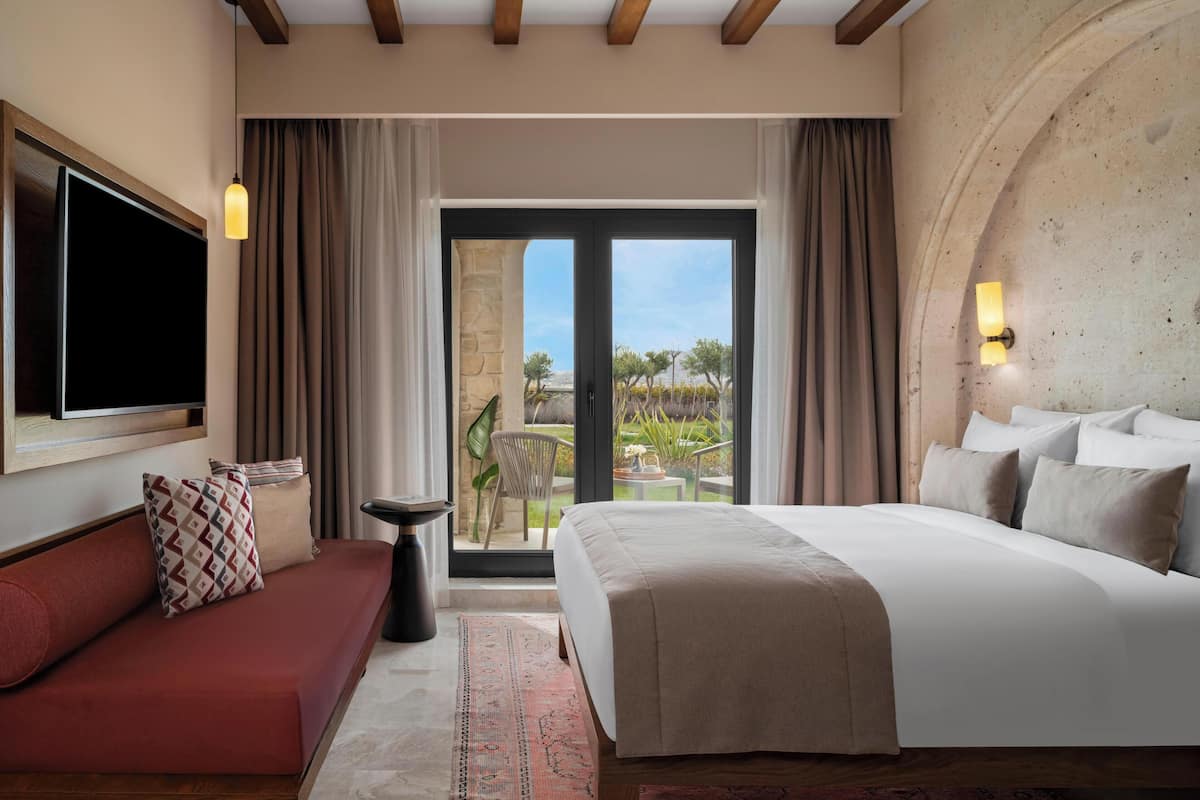 Habitación de hotel con cama, sofá, televisión y vistas al exterior.
