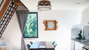 A modern kitchen with a dining area, wooden flooring, and a staircase. - Appartement Duplex Dans une Ancienne Usine (Beaupréau-en-Mauges)