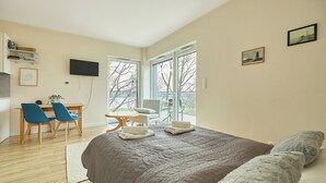 Ein Schlafzimmer mit einem großen Bett, einem Schreibtisch mit Stühlen, einem Fernseher und einem Balkon mit Blick.