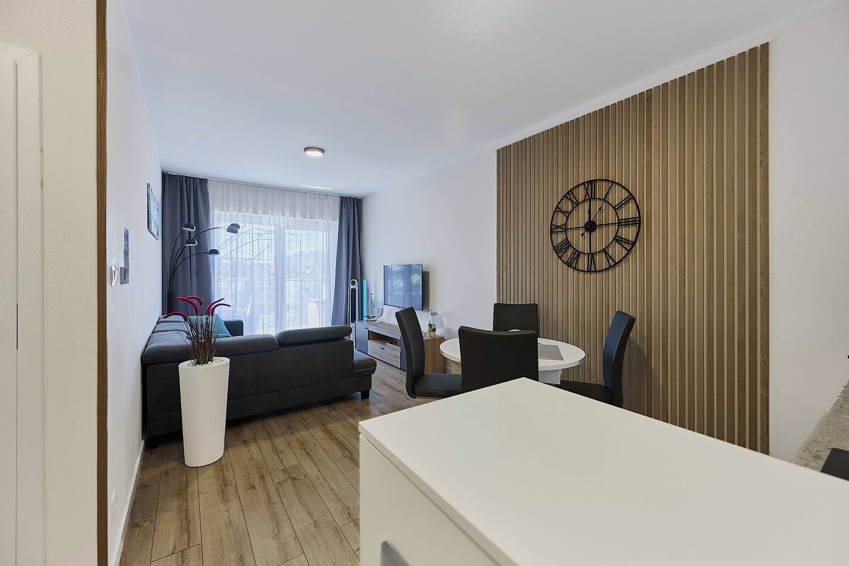 Uma sala de estar moderna com um sofá, uma mesa de jantar e um relógio de parede grande.