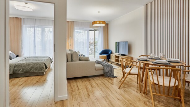 Ein modernes Wohnzimmer mit Sofa, Esstisch und Fernseher.