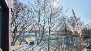 Ein Balkon mit Blick auf kahl stehende Bäume und eine entfernte Brücke.