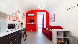 Una sala de estar moderna con una pared de acento roja, un sofá blanco, una mesa de centro blanca y una estantería.