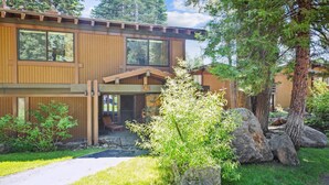 Une maison moderne à deux étages, avec des fondations en pierre, de grandes fenêtres et un porche abrité.