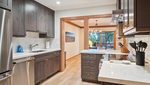 Une cuisine moderne avec des meubles en bois foncé, des appareils électroménagers en acier inoxydable et un plan de travail en marbre.