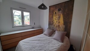 Una camera da letto con un letto, una finestra, un quadro e una cassettiera.