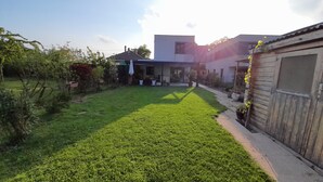 Un cortile residenziale con un prato curato, una piccola zona patio e un capanno di legno.
