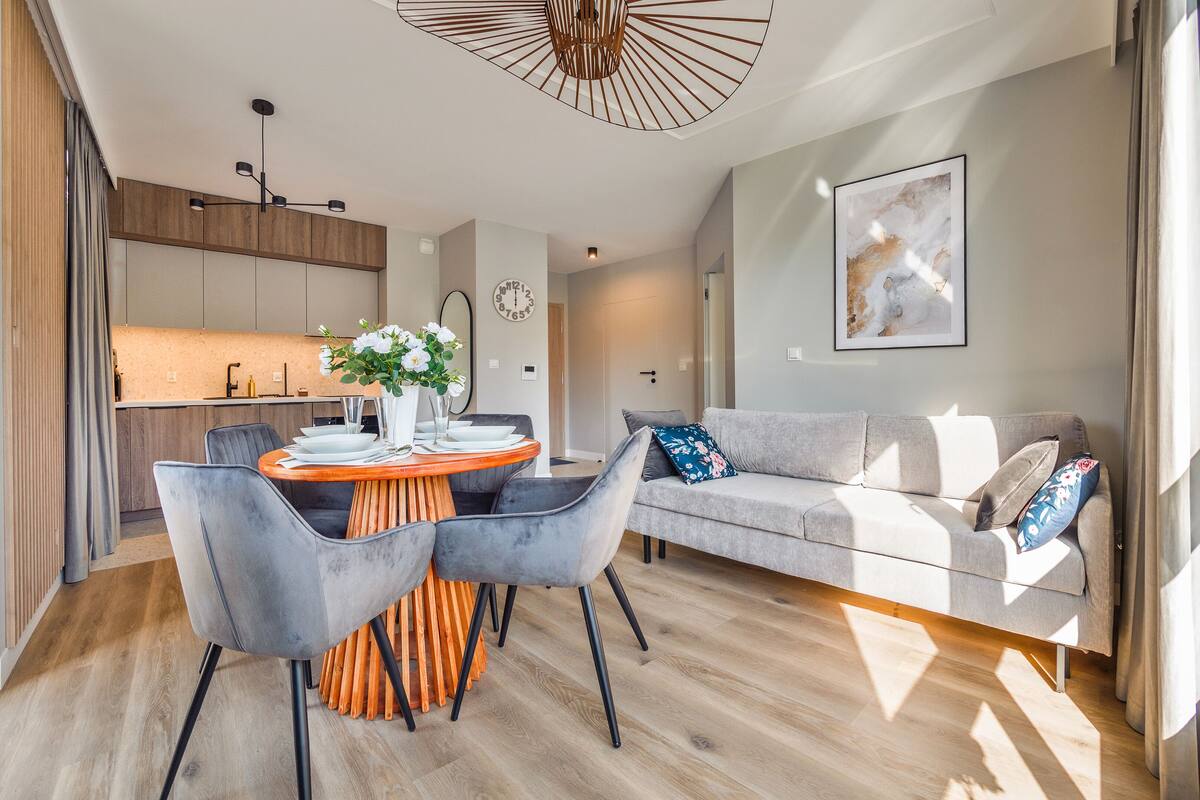 Un espacio de estar moderno con comedor, sofá y cocina al fondo.