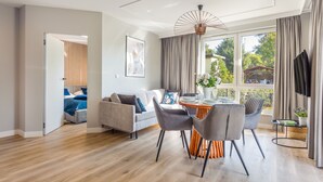 A modern living room with a dining area, large windows, and a view of the outdoors.