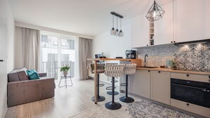 A modern kitchen with a dining area, featuring a bar stool set, a coffee machine, and a pendant light.