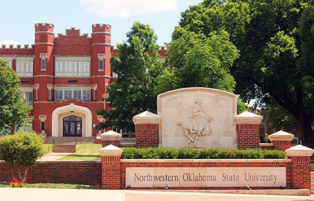 A brick building with a large sign reading "Northwestern Oklahoma State University" and a statue in front.