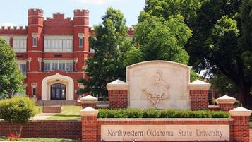 A brick building with a large sign reading "Northwestern Oklahoma State University" and a statue in front.