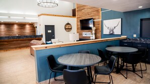 A modern interior with a reception desk, seating area, and a TV mounted on the wall. - OK Welcome Home Hotel (Alva)